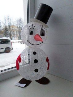 a snowman made out of plastic sitting on top of a window sill