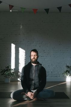 a man is sitting in the middle of a yoga pose with his feet crossed and eyes closed