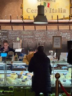 people standing in line at a food stand with menus on the wall behind them