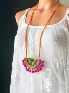 a woman wearing a white top with a colorful necklace hanging from it's neck