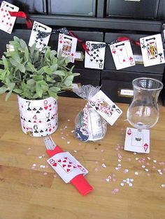 a table with playing cards on it next to a potted plant and some other items