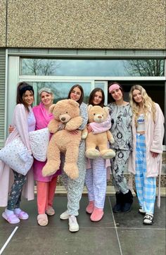 four girls are holding teddy bears in front of a building