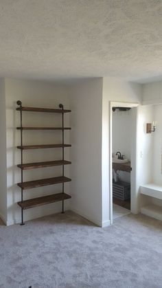 an empty room with shelving unit in the corner