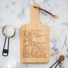 a wooden cutting board with writing on it next to utensils and spoons