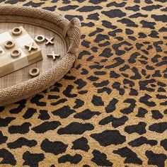 an animal print rug with wooden blocks and buttons on it, next to a basket