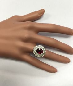 a woman's hand with a ring on top of it and a red stone in the middle