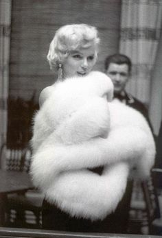 a woman in a white fur coat standing next to a man