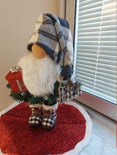 a stuffed animal wearing a hat and scarf sitting on top of a red rug next to a window