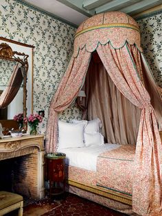 a canopy bed sitting in the middle of a bedroom next to a dresser and mirror