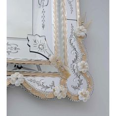 an ornate mirror with flowers and pearls on the edge is shown in gold, white and silver