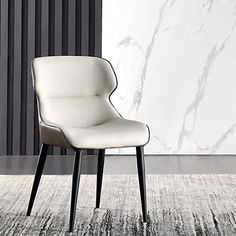 a white chair sitting on top of a rug in front of a black and white wall