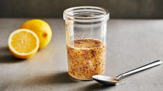 a glass jar filled with food sitting next to two lemons and a measuring spoon