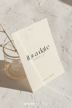 a card that reads it's a date sitting next to a vase with a plant in it