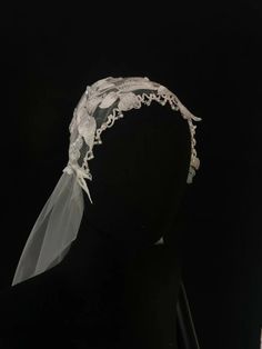 a white veil on top of a mannequin's headdress in front of a black background