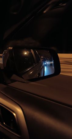 a car's rear view mirror is shown in the reflection of another car at night