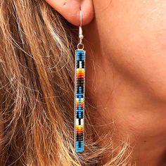 a close up of a woman's face wearing earrings with beads on them and dangling from the ear