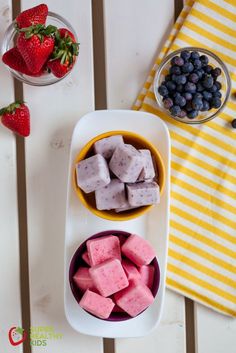 two bowls with blueberries, strawberries and marshmallows next to each other