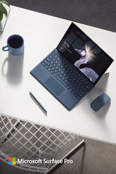 an open laptop computer sitting on top of a white table next to a cup of coffee