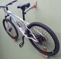 a white and black bike hanging on the side of a building with no wheel hubs