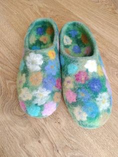 a pair of slippers sitting on top of a wooden floor covered in colorful flowers