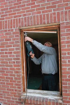 a man is using a power drill on a brick wall in an unfinished window sill