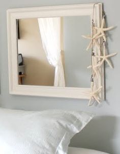 a mirror hanging on the side of a wall above a bed with white sheets and pillows