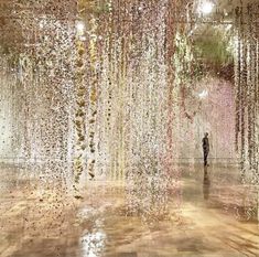 a person standing in front of a large display of flowers and leaves hanging from the ceiling