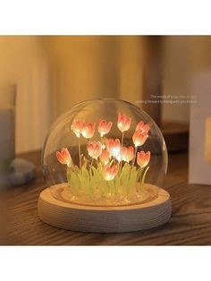 there is a glass dome with flowers in it on top of a wooden table and the light shines brightly