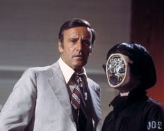 two men in suits and ties stand next to each other with masks on their faces