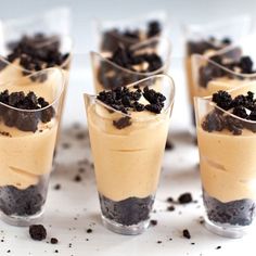 four glasses filled with desserts sitting on top of a table