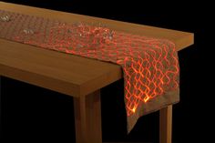 a table topped with a red cloth covered in orange lights next to a wooden table