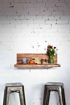 two metal stools in front of a white brick wall