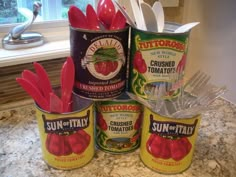 four canisters with spoons and utensils in them on a kitchen counter