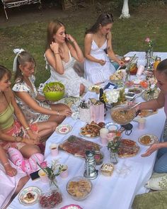 a group of people sitting around a table with food on it and plates in front of them