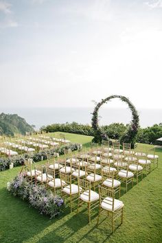 an outdoor ceremony set up with chairs and flowers on the lawn, surrounded by greenery