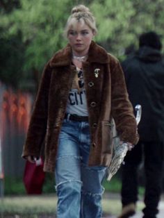 a woman walking down the street with her hand in her pocket and wearing a fur coat