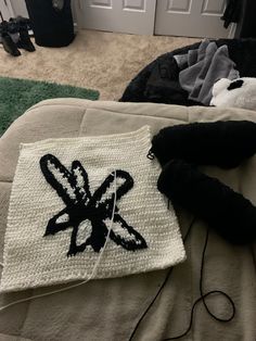 a crocheted piece of cloth sitting on top of a bed next to a pair of black shoes