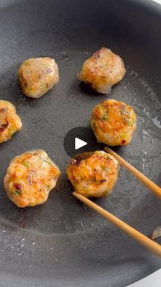 some food is being cooked in a frying pan with chopsticks on the side