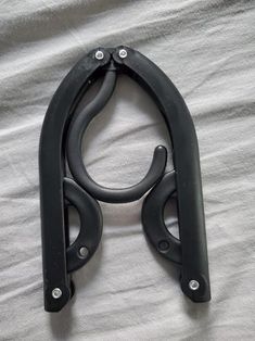 a pair of black scissors laying on top of a white bed sheet with the handles extended