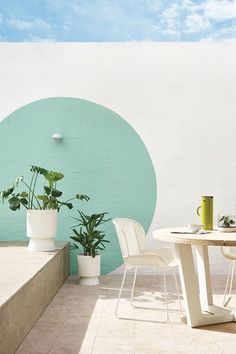 there is a table and two chairs on the outside patio with a potted plant next to it