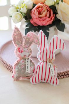 two bunny shaped cookies sitting on top of a pink plate next to a vase with flowers