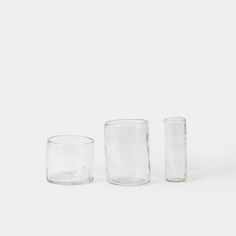 three clear glass cups sitting on top of each other in front of a white background