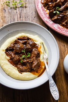 a plate with mashed potatoes, meat and gravy