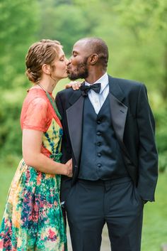 a man in a tuxedo kissing a woman in a colorful dress and bow tie