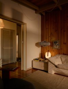 a living room with wood paneling and a white couch next to a wooden wall