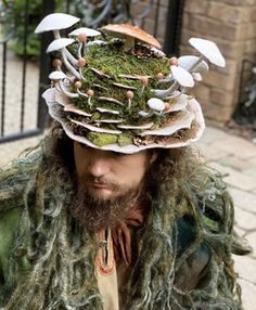 a man wearing a hat with mushrooms on it's head and moss growing out of the top