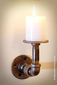 a candle that is sitting on a wall next to a light fixture in a bathroom