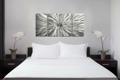 a bed with white sheets and two vases on top of the bedspread