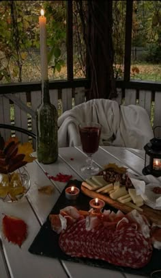 a table topped with meat and cheese covered in sauces next to a lit candle