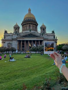 people sitting on the grass in front of a building with a dome and gold roof